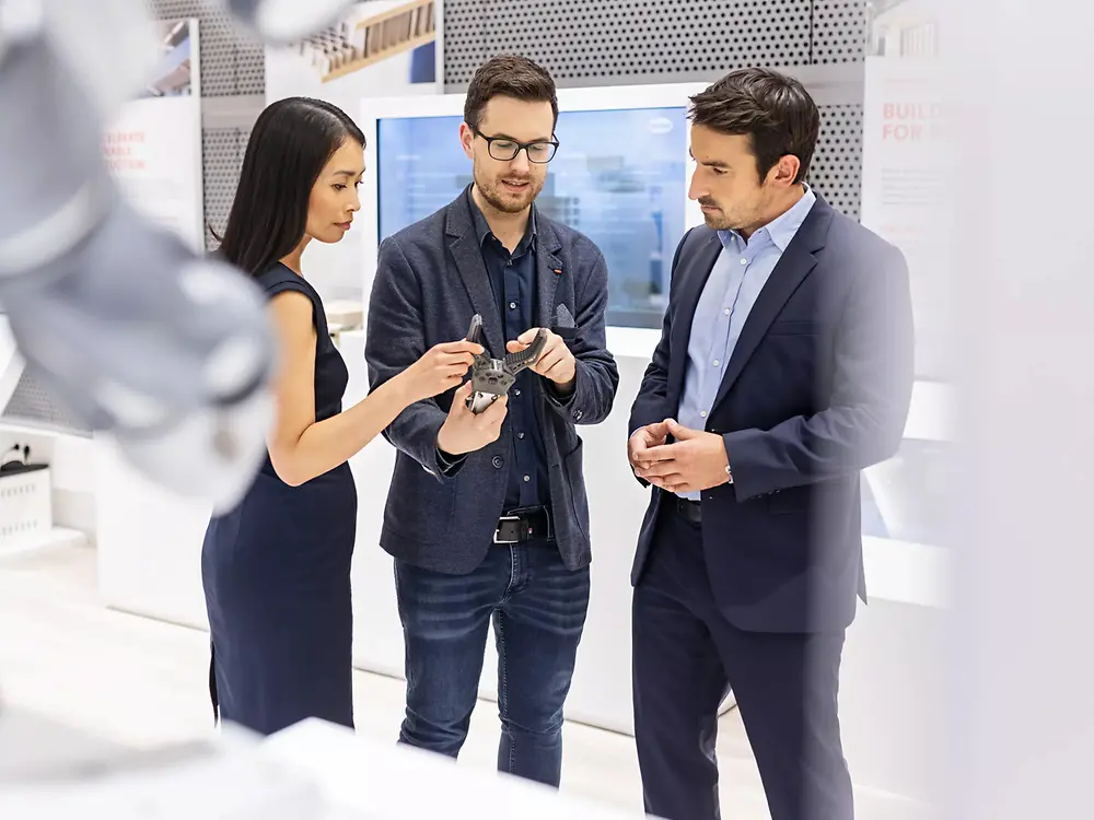 A customer experience tour guide presents two customers an exhibit at the Henkel Adhesive Technologies - Inspiration Center Düsseldorf.